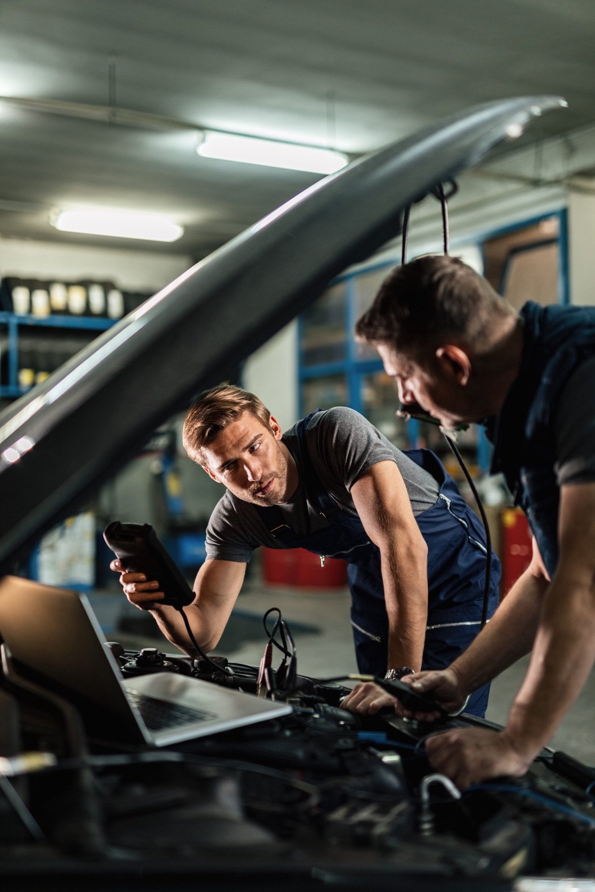 Technicians inspecting a car engine with diagnostic equipment