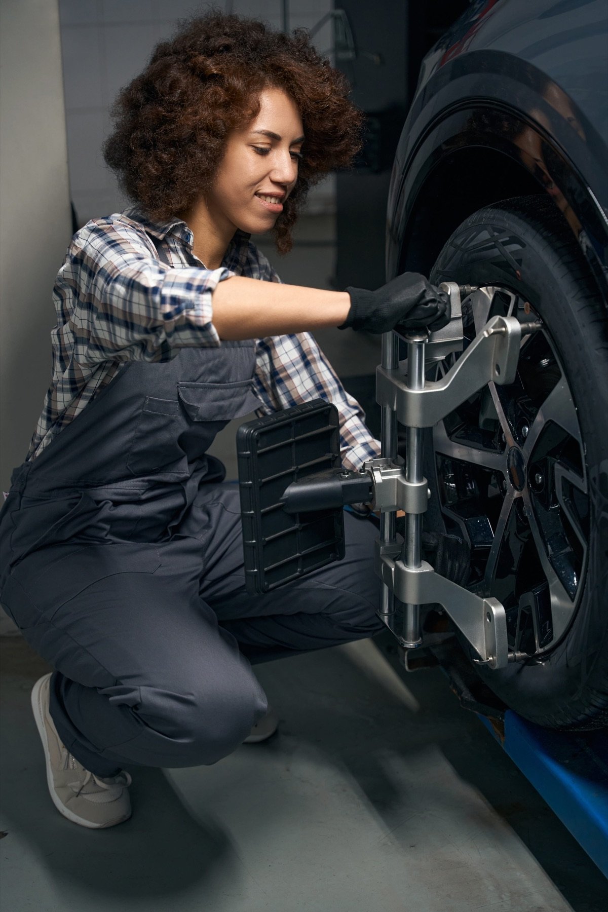 Technician adjusting wheel alignment equipment in the workshop